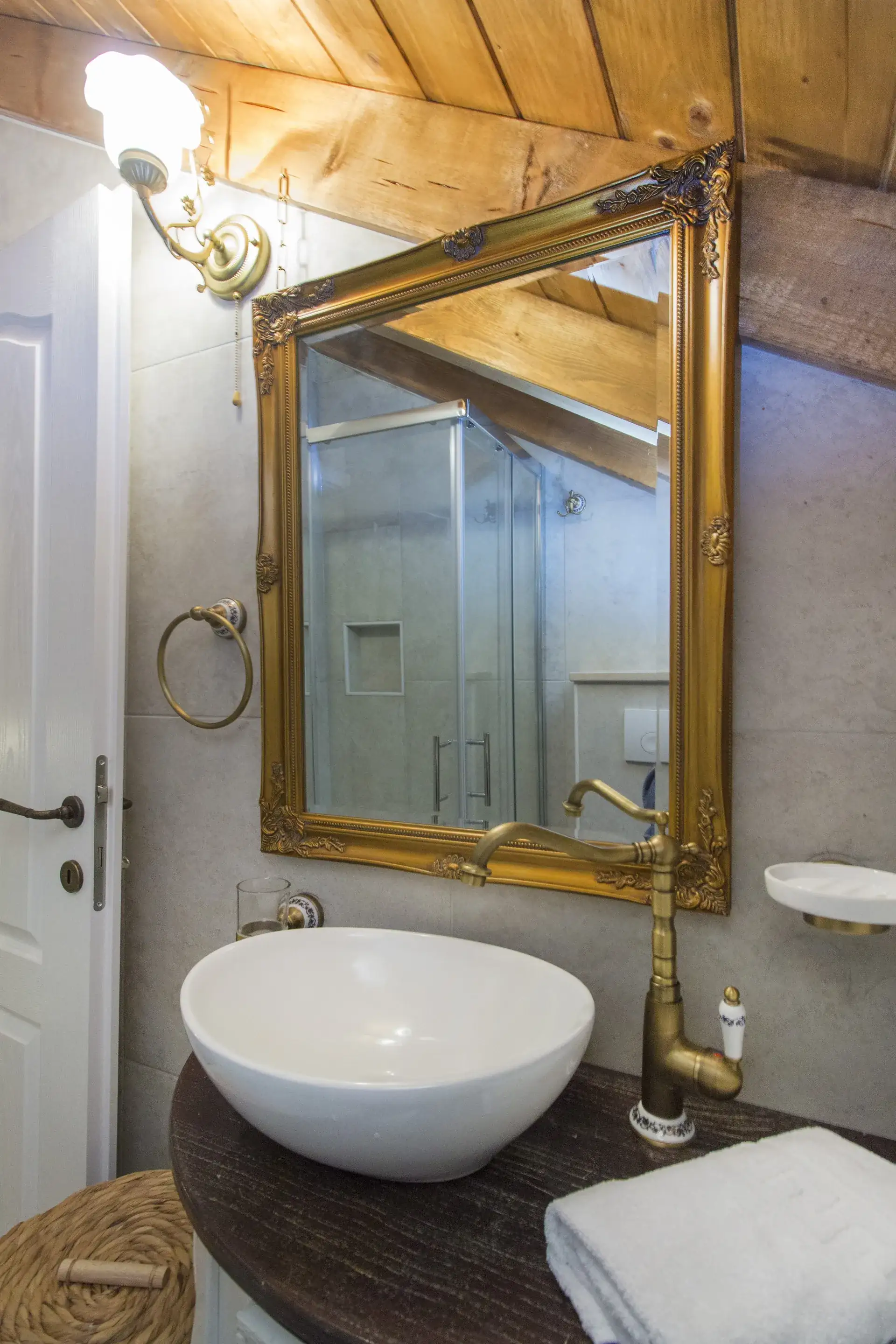 Round vessel sink below a gold-framed mirror in the second bathroom