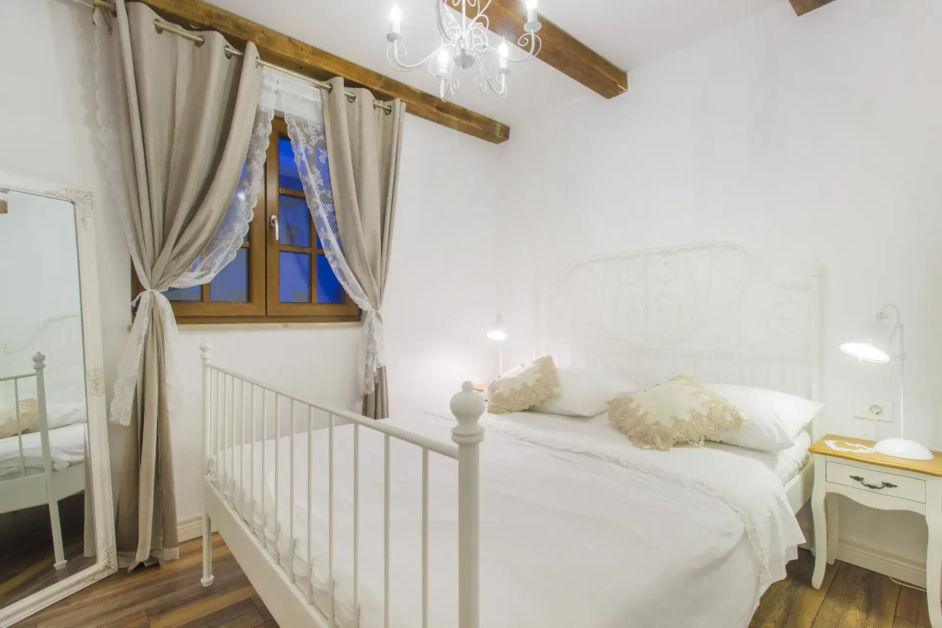 Wrought-iron bed with fresh white linens beside the window