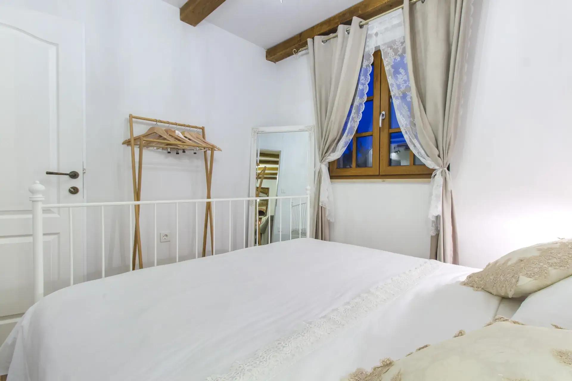 Double bed beside the curtained window, with a full-length mirror