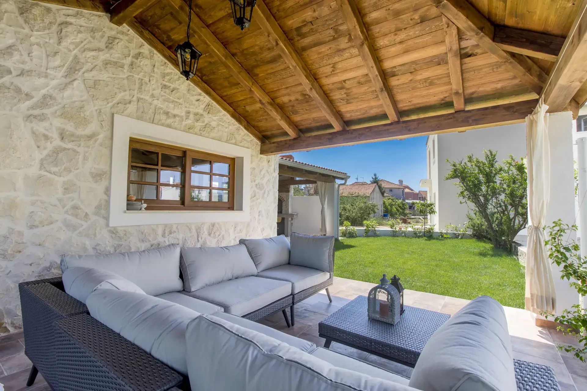 Corner sofa on the covered terrace with the garden and sea light beyond