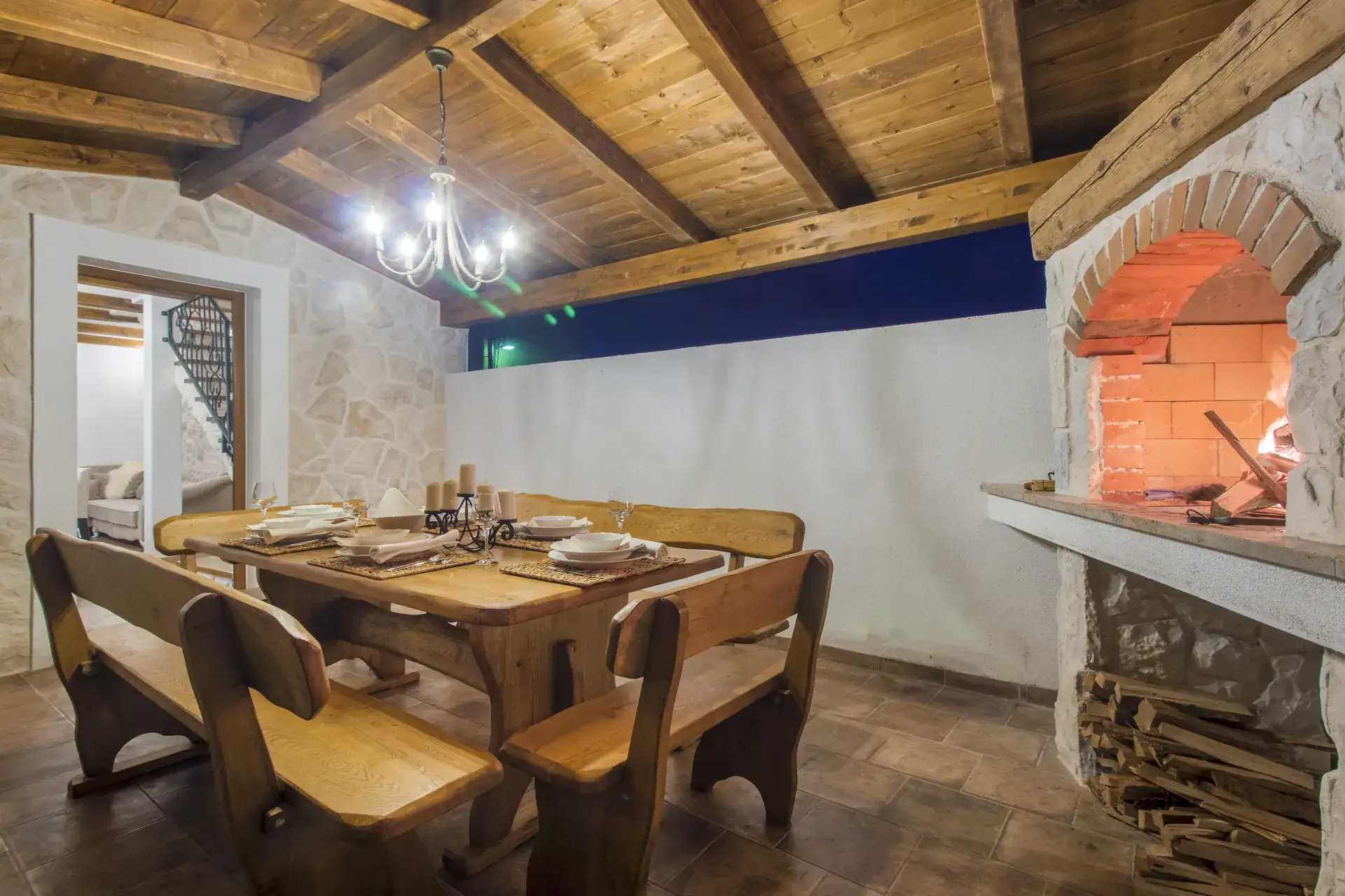 Wooden dining table beside the stone BBQ with the fire lit