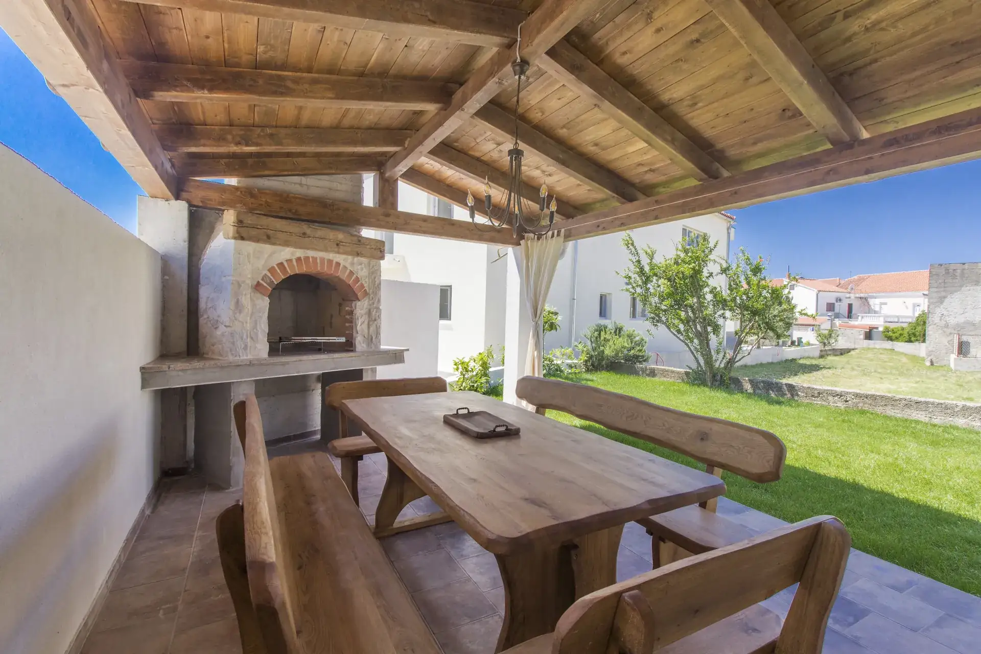 Stone BBQ and long wooden table under the covered terrace at House Leila