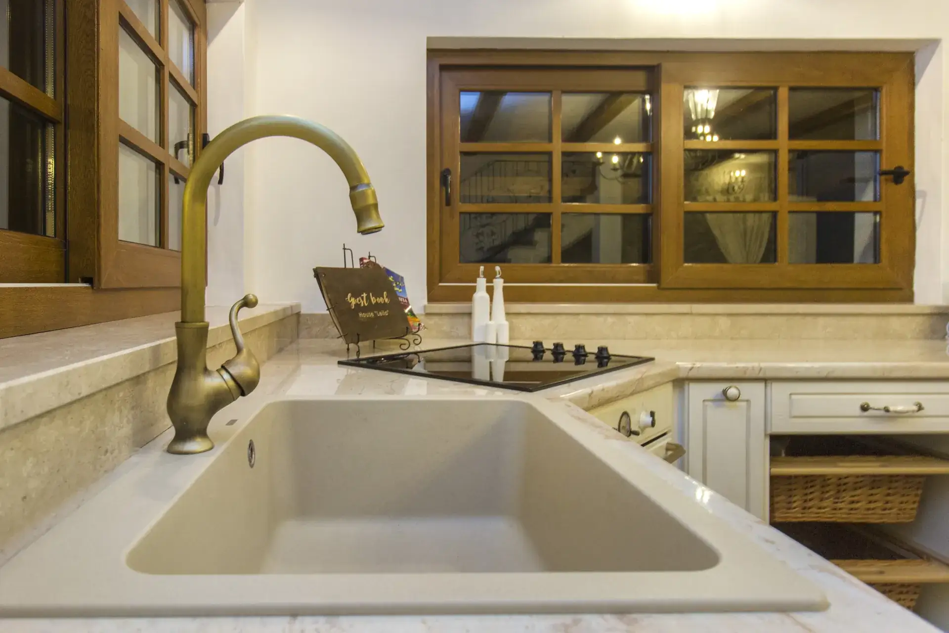 Brass tap and sink below the wooden-framed kitchen windows