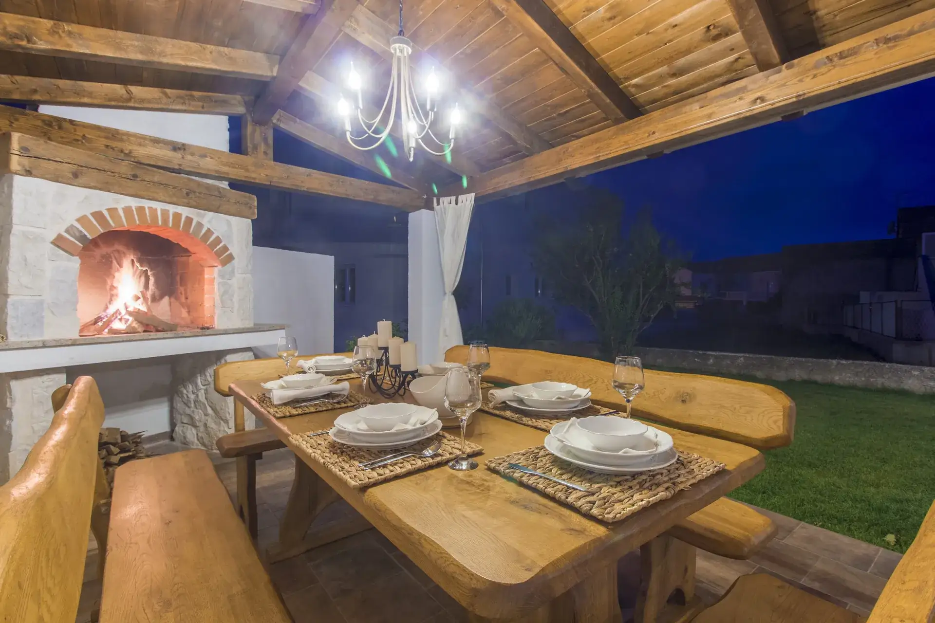 Dinner laid on the long wooden table with the stone BBQ burning behind