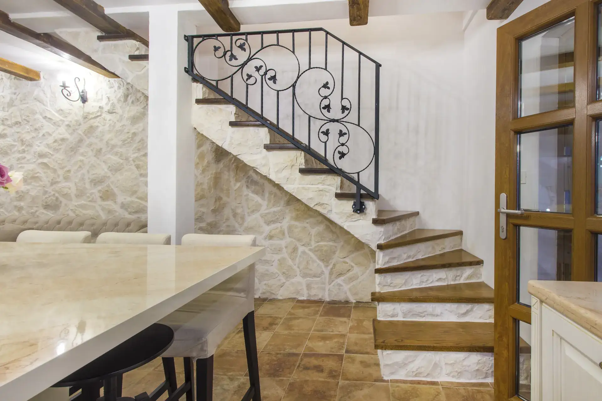 Wrought-iron staircase against the exposed stone wall